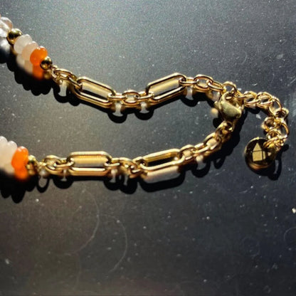 Gold chain bracelet with beads on a dark background
