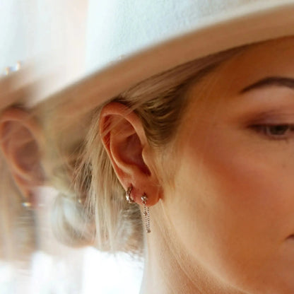 Close-up of a person wearing a white hat with a blurred background. Mini Hex Hoop Earrings KatyB Jewellery