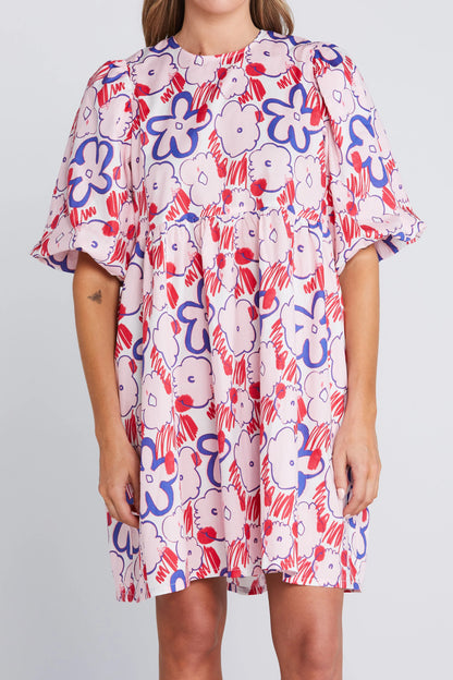 Woman wearing a colorful floral dress on a plain background