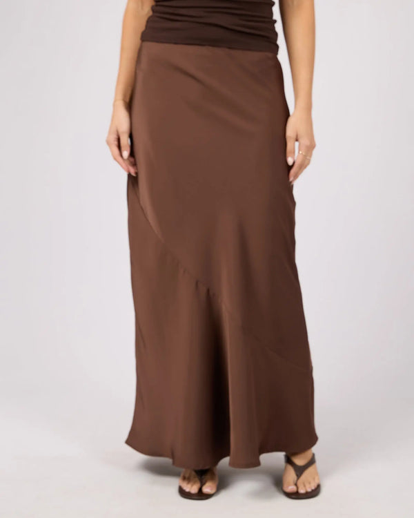 Brown long skirt worn by a person on a white background. Carter Maxi Skirt Brown - The Rose Edit