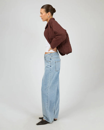 Woman wearing a brown jacket and light blue jeans on a white background. Archer Stitched Jacket Cherry - The Rose Edit