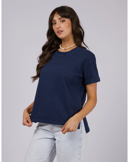 Woman wearing a navy blue t-shirt and light blue jeans on a gray background
