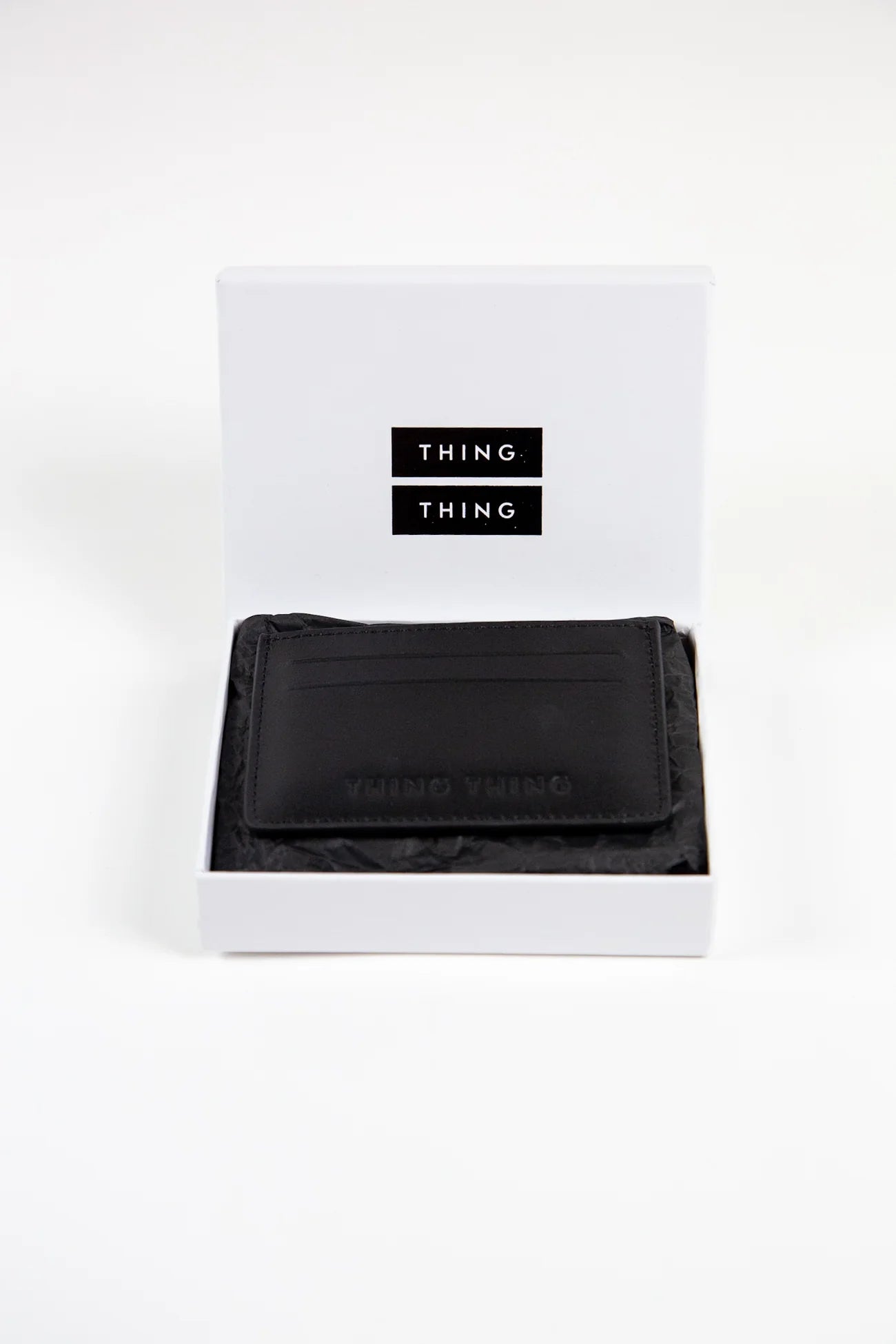 Black wallet in a white box with 'THING' branding on a white background