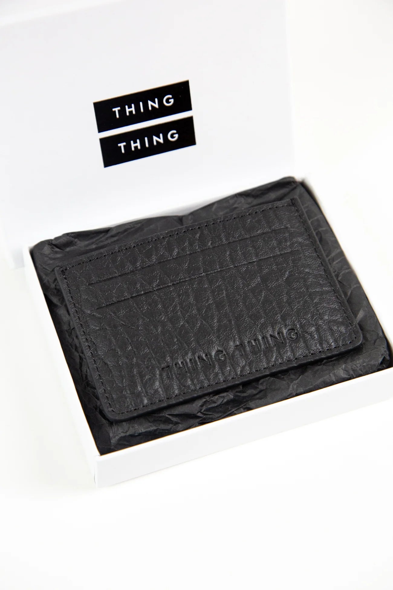 Black textured wallet with 'THING' branding on a white background