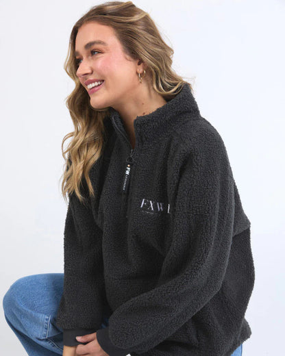 Woman wearing a black fleece pullover with a logo on a white background