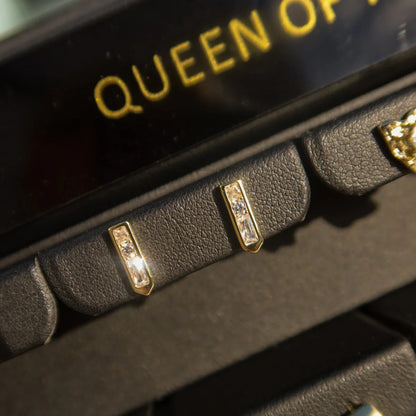 Close-up of a black and gold product with 'QUEEN OF' text.