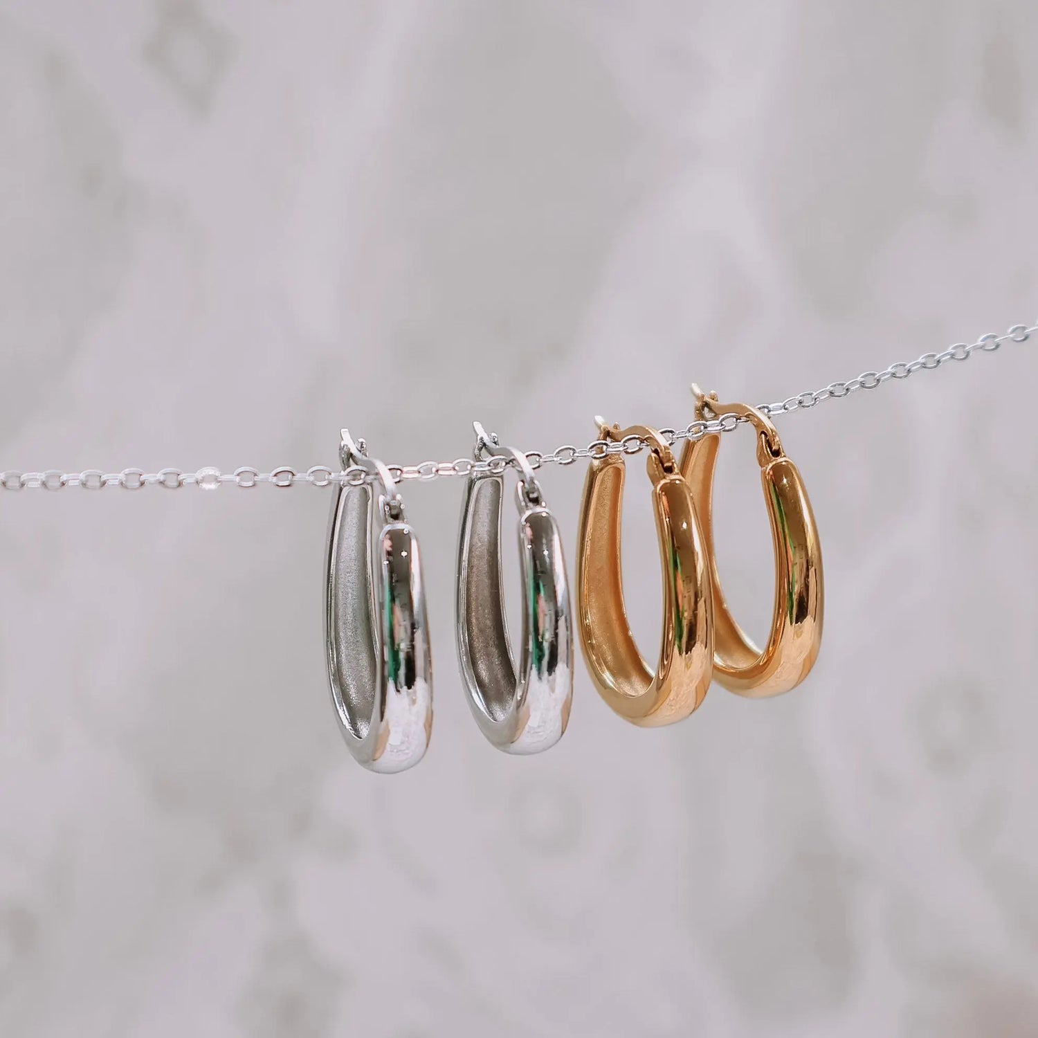 Gold and silver Maeve Hoops hanging on chain — both colourways side by side on neutral background