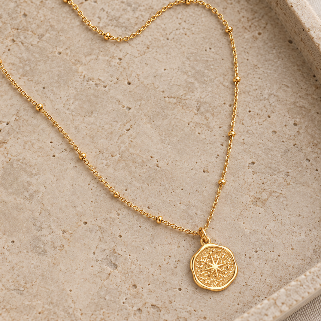 Sol Necklace gold satellite chain and starburst pendant on a natural stone tray