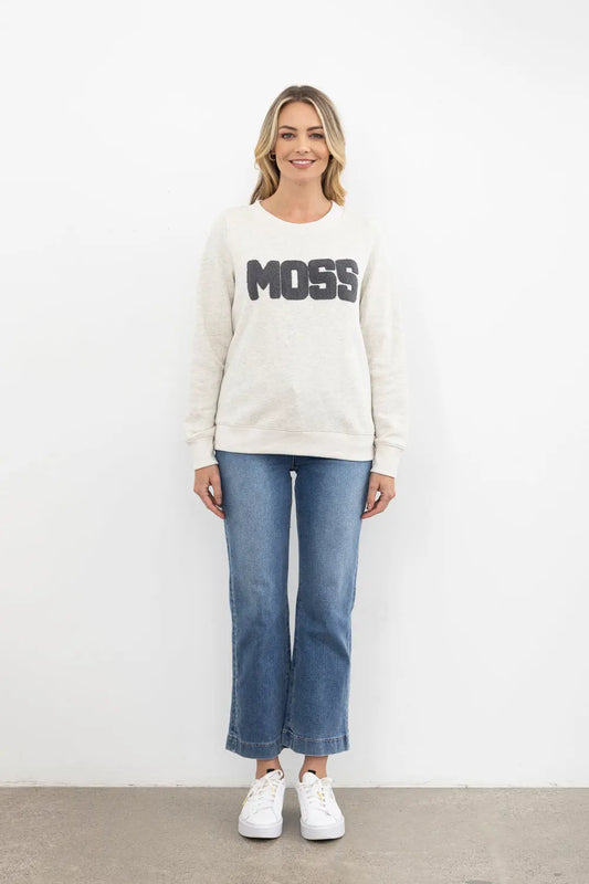 Woman wearing a white sweatshirt with 'MOSS' text and blue jeans on a white background