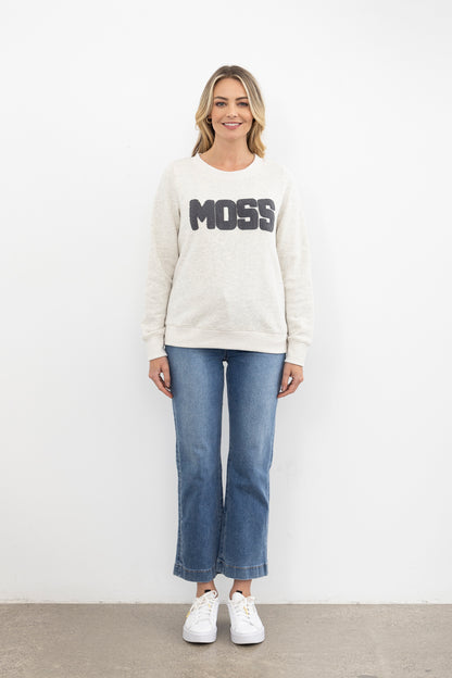 Woman wearing a white sweatshirt with 'MOSS' text and blue jeans on a white background
