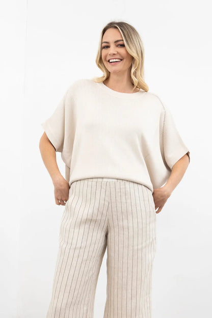 Woman wearing a beige sweater and pants on a white background