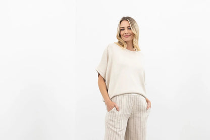 Woman wearing a beige sweater and striped pants on a white background