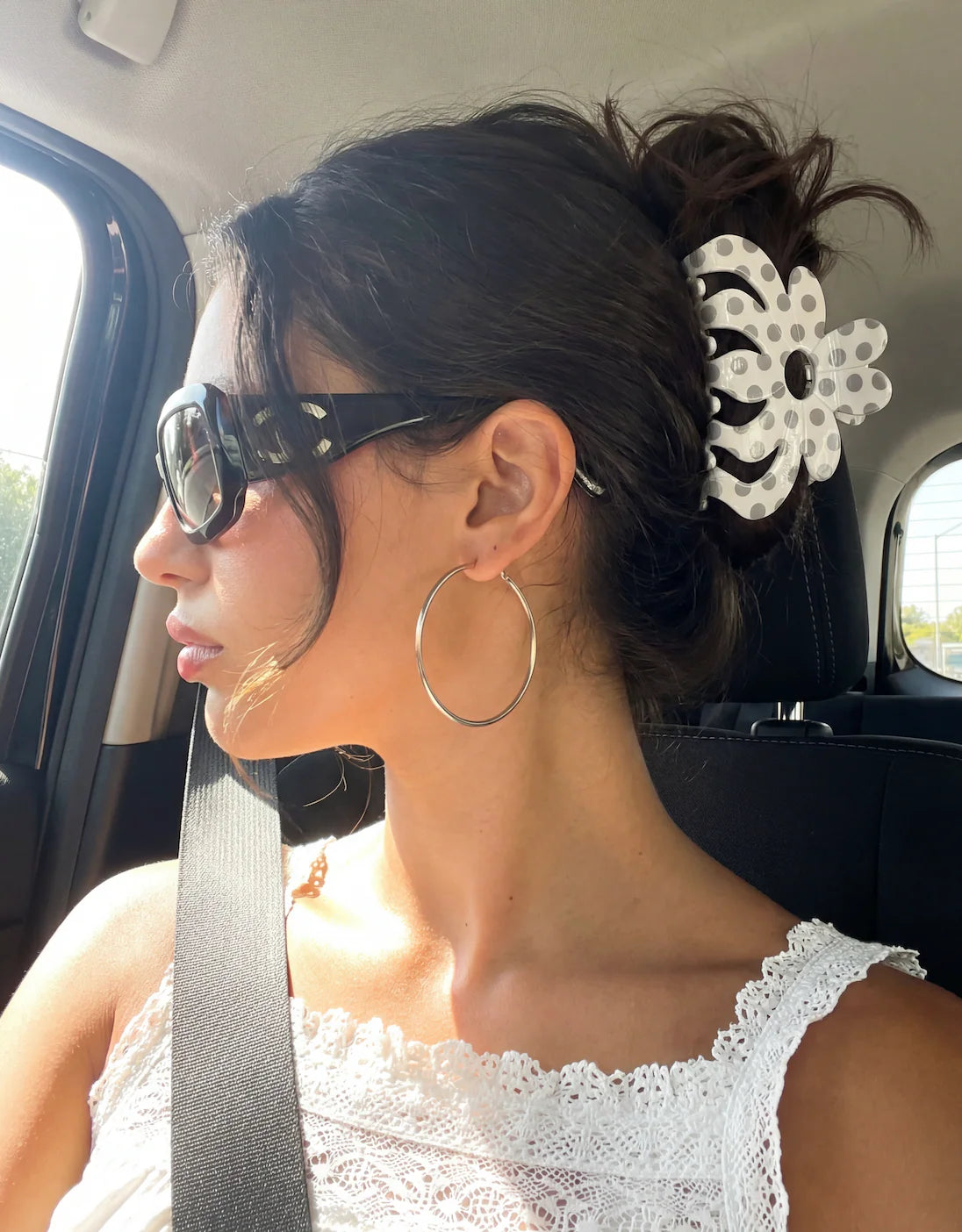 Woman in a car wearing sunglasses and a white lace top with a decorative hairpiece. Buttermilk Rebekah Claw Clip Chia Pudding - The Rose Edit