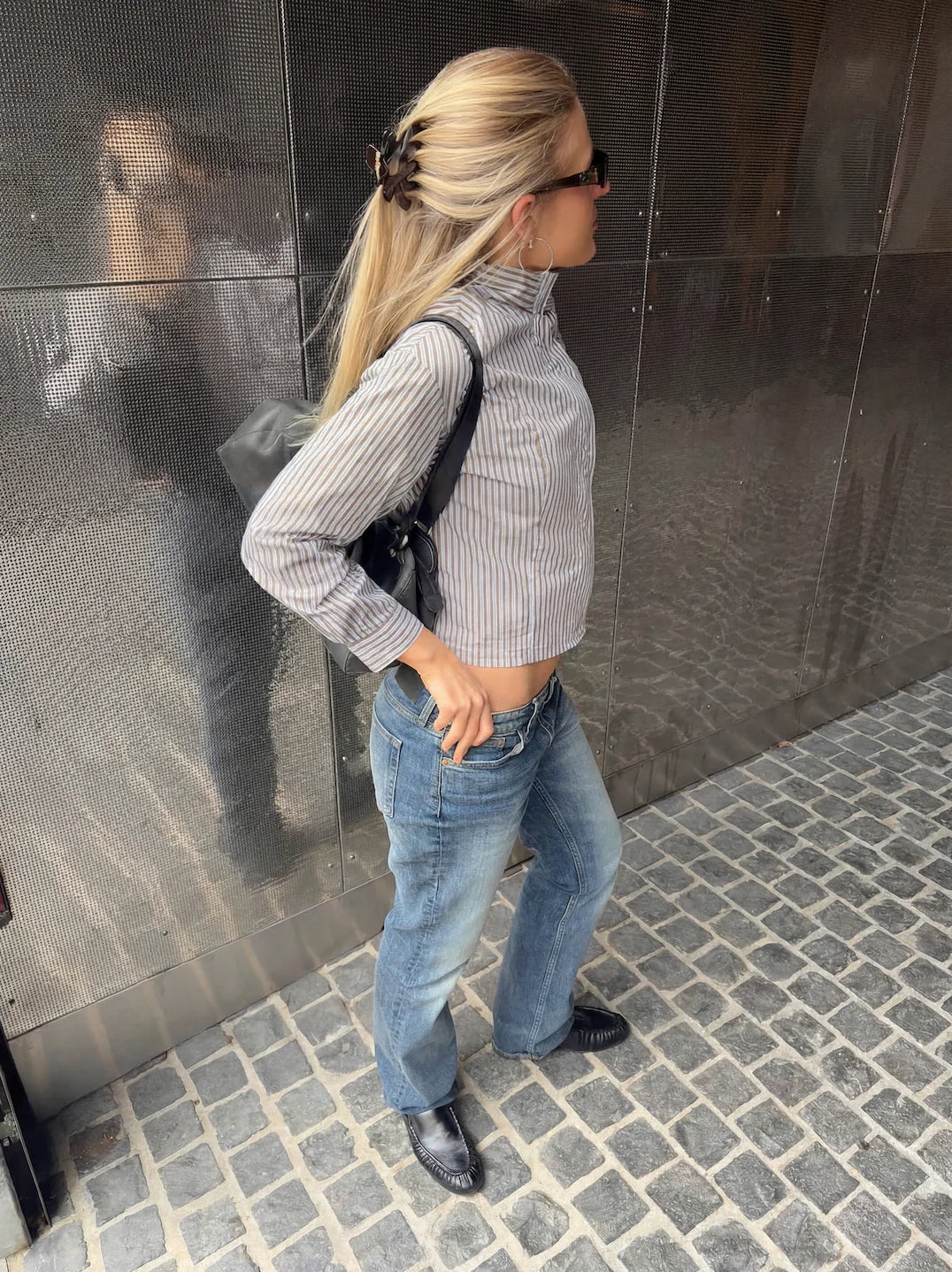 Woman standing against a reflective wall wearing a striped shirt and jeans. Buttermilk Rebekah Claw Clip Coffee Table - The Rose Edit