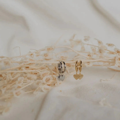 Silver and gold heart hoop earrings flat lay on dried floral linen texture. heart hoop earrings KatyB Jewellery