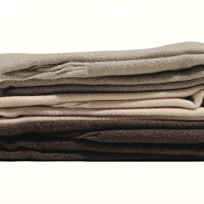 Stack of folded blankets in various neutral colors on a white background. Simple Scarf Taupe - The Rose Edit