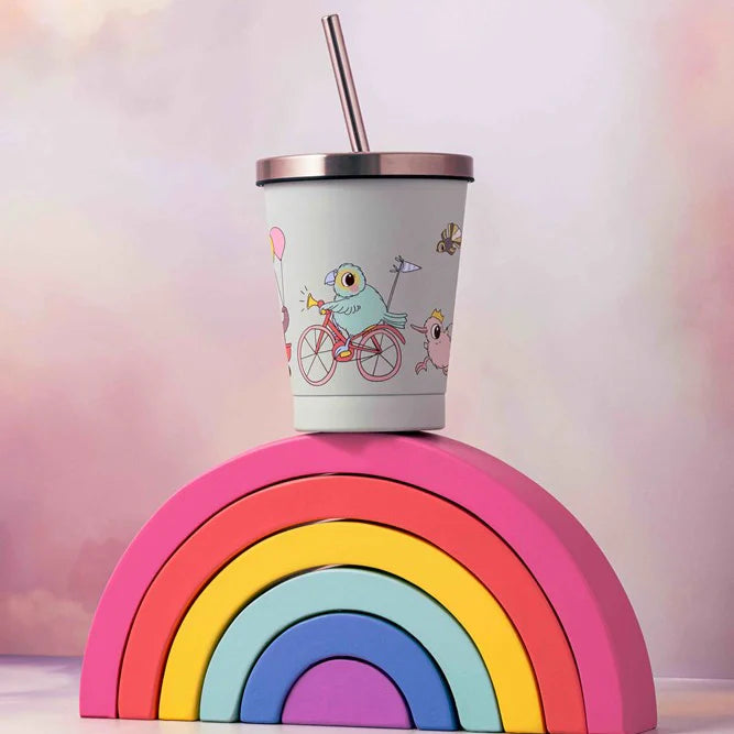 Children's tumbler with cartoon design on a rainbow stand against a soft pink background