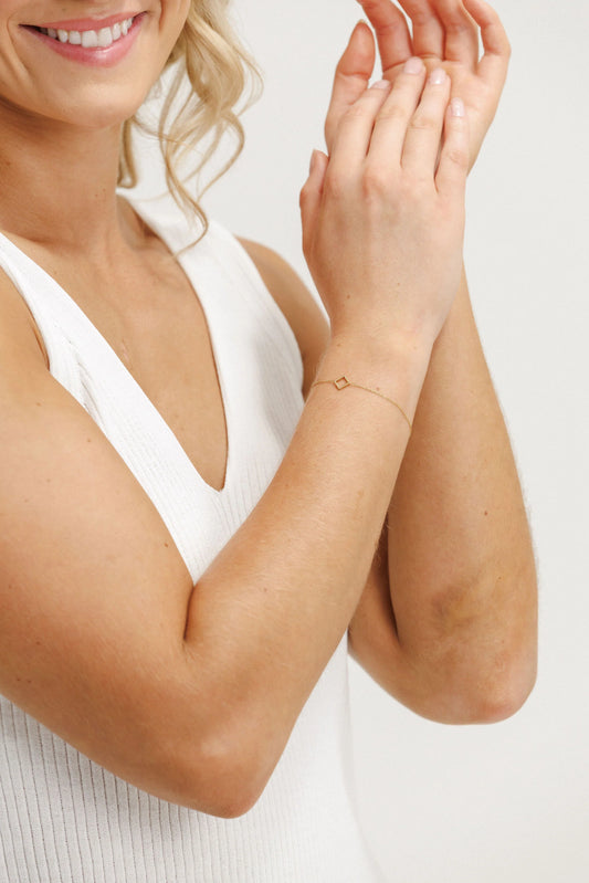 Woman wearing a delicate bracelet on a plain background