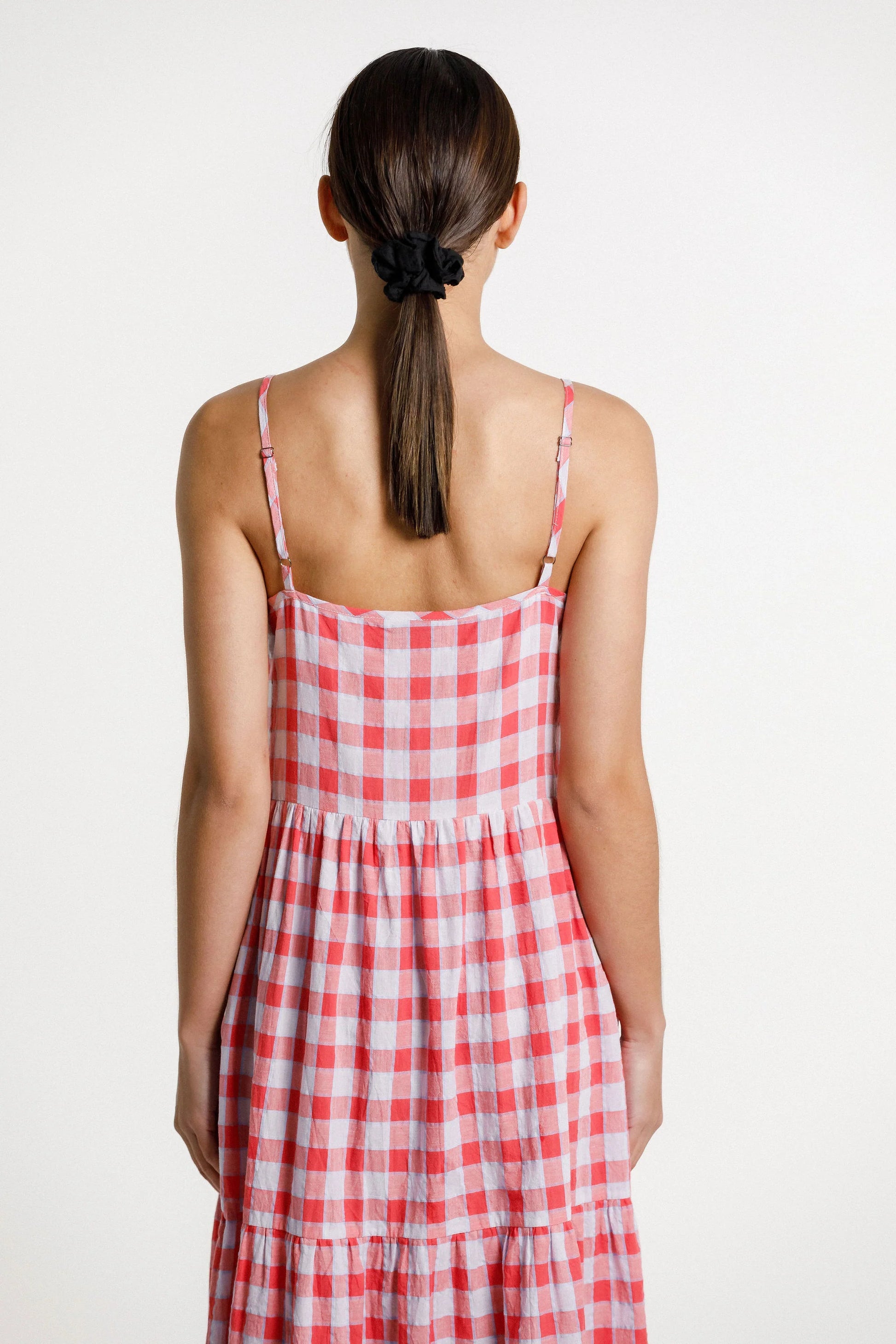 Woman wearing a red and white checkered dress on a plain background