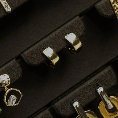 Close-up of gold and silver earrings in a black jewelry box
