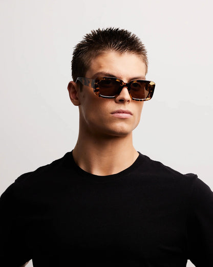 Person wearing sunglasses and a black shirt against a light gray background