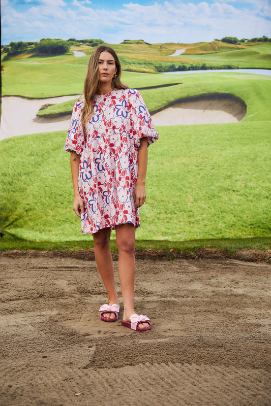 Woman in a floral dress standing on a golf course
