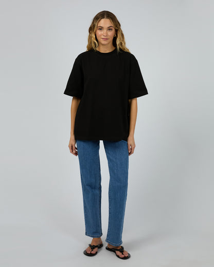 Person wearing a black t-shirt and blue jeans on a plain background