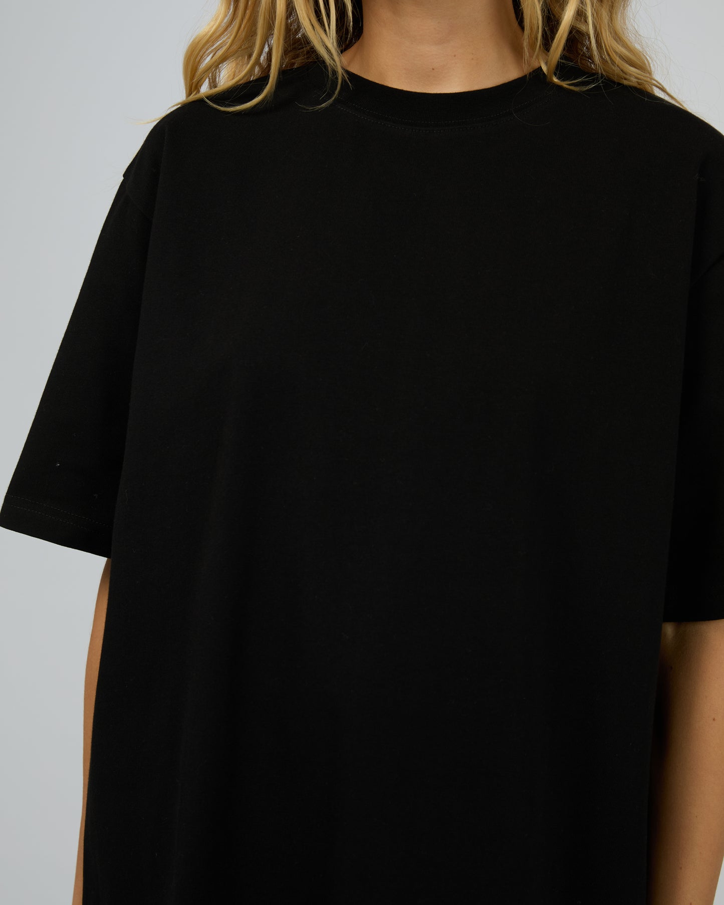 Black t-shirt worn by a person on a plain background