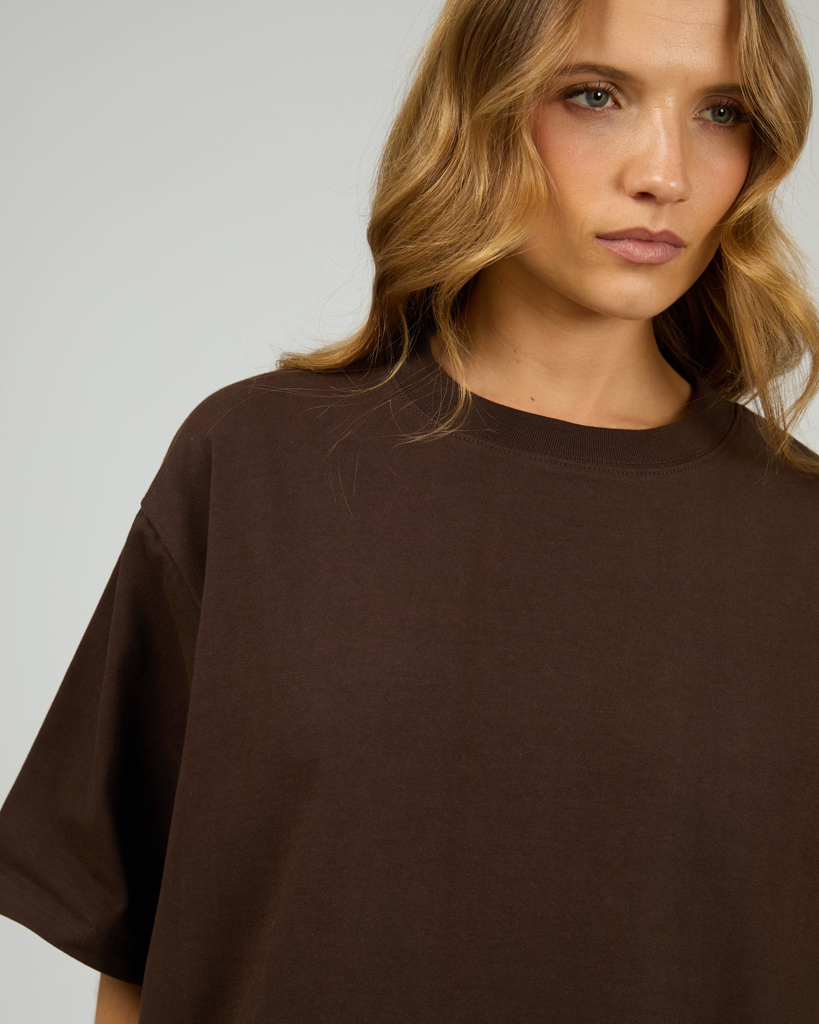Woman wearing a brown oversized t-shirt against a plain background. Core Oversized Tee Chocolate - The Rose Edit