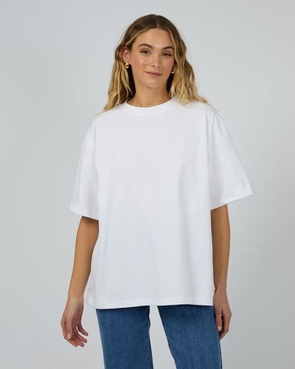 Woman wearing a white oversized t-shirt and blue jeans on a plain background