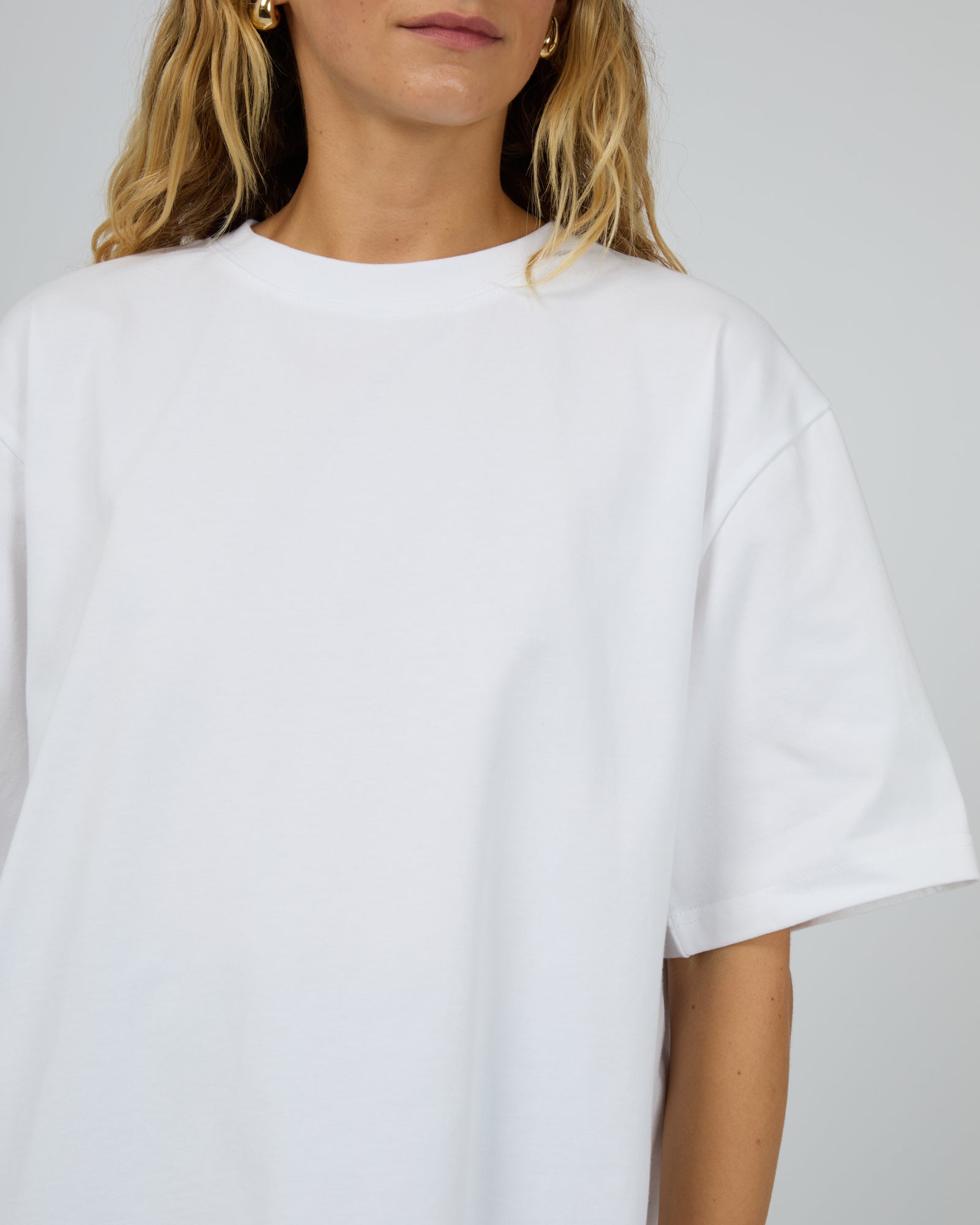 Person wearing a plain white t-shirt against a neutral background