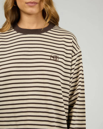 Person wearing a striped long-sleeve shirt with a logo on a plain background. Silent Theory Foundation Stripe Long Sleeve Tee Chocolate - The Rose Edit