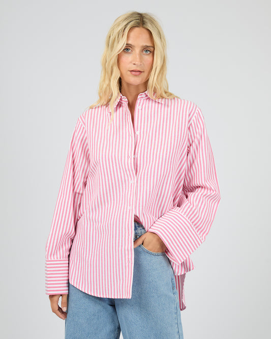 Woman wearing a pink and white striped shirt with blue jeans on a gray background