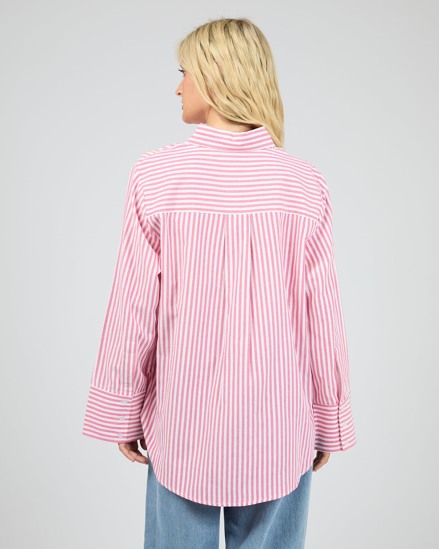 Person wearing a pink and white striped shirt on a gray background