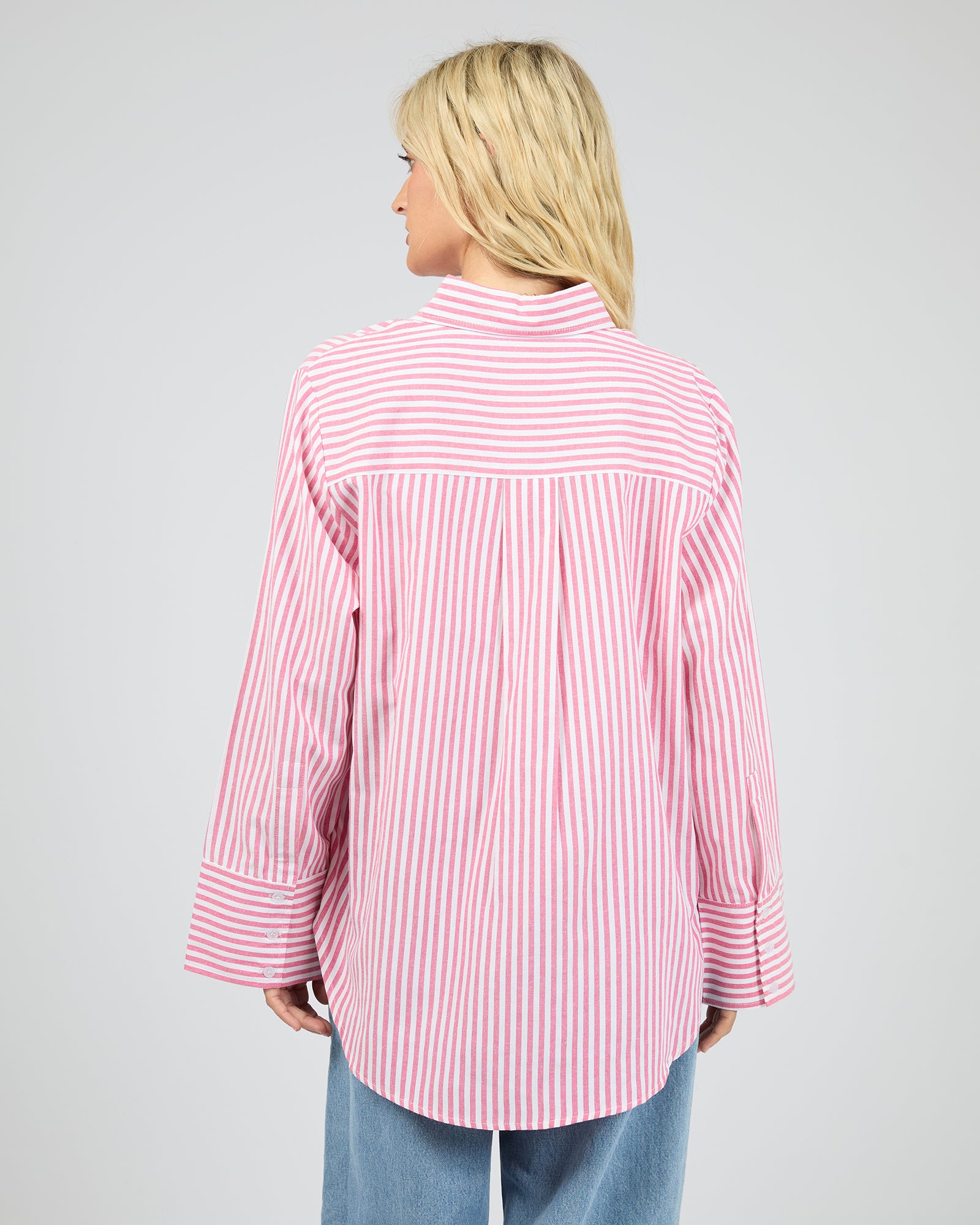 Person wearing a pink and white striped shirt on a gray background