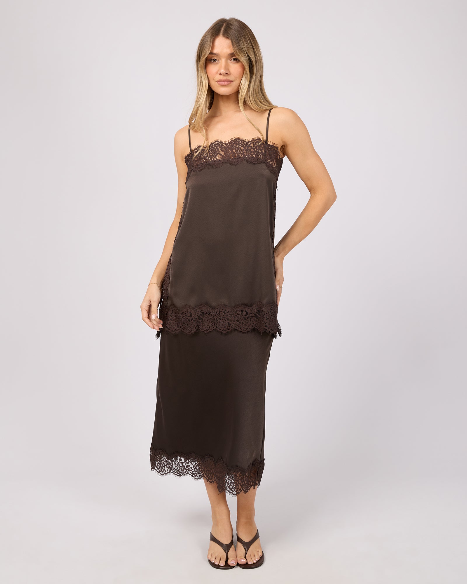 Woman wearing a brown slip dress with lace details on a white background. Hava Lace Skirt Coffee - The Rose Edit