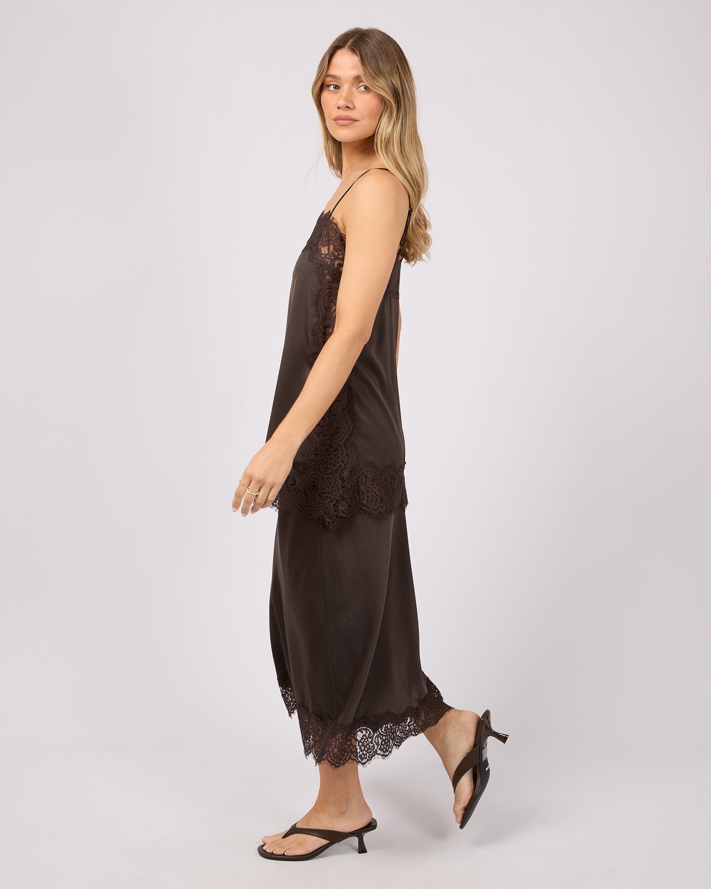 Woman wearing a brown slip top and skirt with lace details on a white background. Hava Lace Skirt Coffee - The Rose Edit