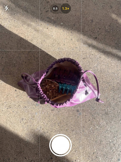 Purple drawstring bag with items on a concrete surface