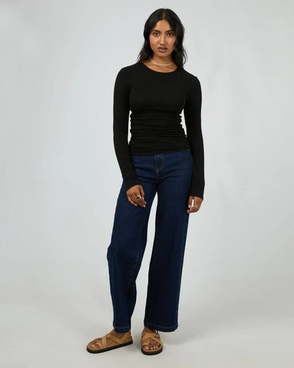 Woman wearing a black long-sleeve top and blue jeans on a white background.Kylie Long Sleeve Top Black - The Rose Edit