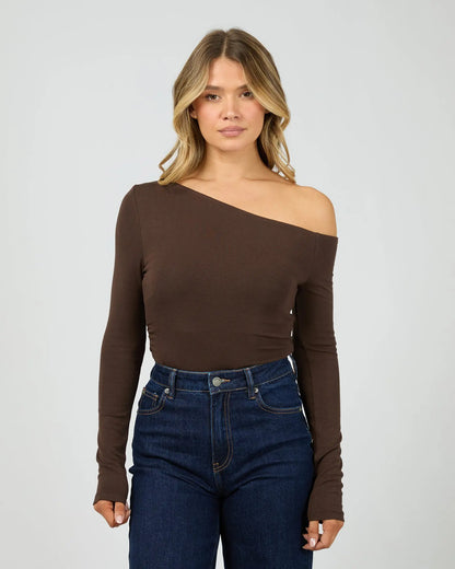 Woman wearing a brown off-shoulder top and blue jeans on a white background. Kylie Off Shoulder L/S Top Brown Front View - The Rose Edit