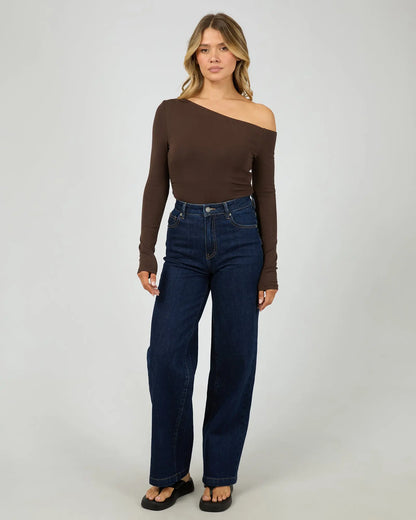 Woman wearing a brown off-shoulder top and blue jeans on a white background. Kylie Off Shoulder L/S Top Brown Full Body View - The Rose Edit