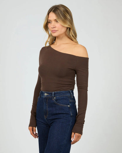 Woman wearing a brown off-shoulder top and blue jeans on a white background. Kylie Off Shoulder L/S Top Brown Side View - The Rose Edit
