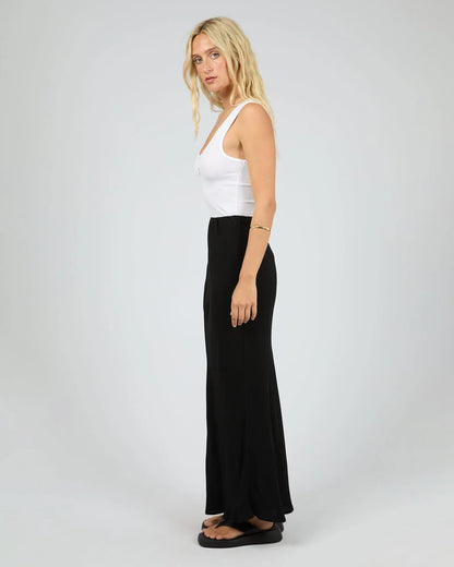 Woman wearing a white tank top and black skirt on a plain background. Maybelle Slip Skirt Black - The Rose Edit