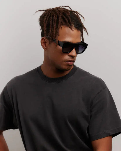 Man wearing black sunglasses and a black t-shirt against a plain background