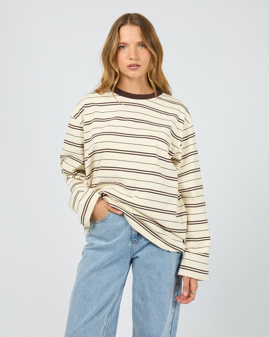 Woman wearing a striped sweater and jeans on a plain background. Stripe Long Sleeve Tee Chocolate - The Rose Edit