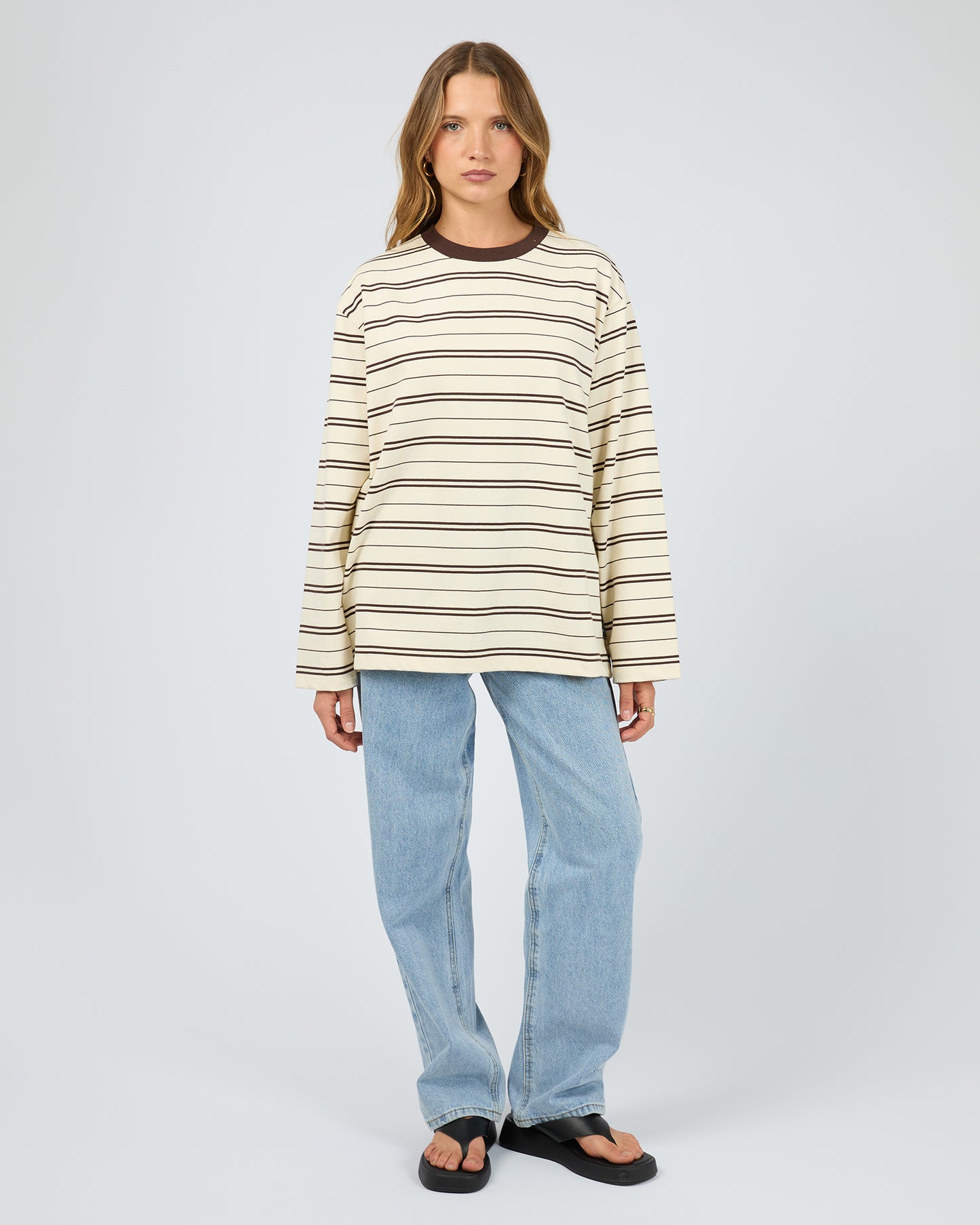 Person wearing a striped sweater and jeans on a white background. Stripe Long Sleeve Tee Chocolate - The Rose Edit