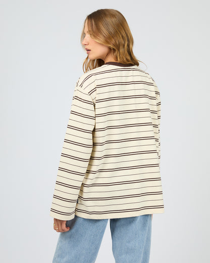 Woman wearing a striped sweater and jeans on a plain background. Stripe Long Sleeve Tee Chocolate - The Rose Edit