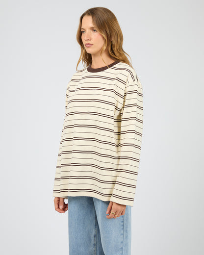 Woman wearing a striped sweater and jeans on a plain background. Stripe Long Sleeve Tee Chocolate - The Rose Edit