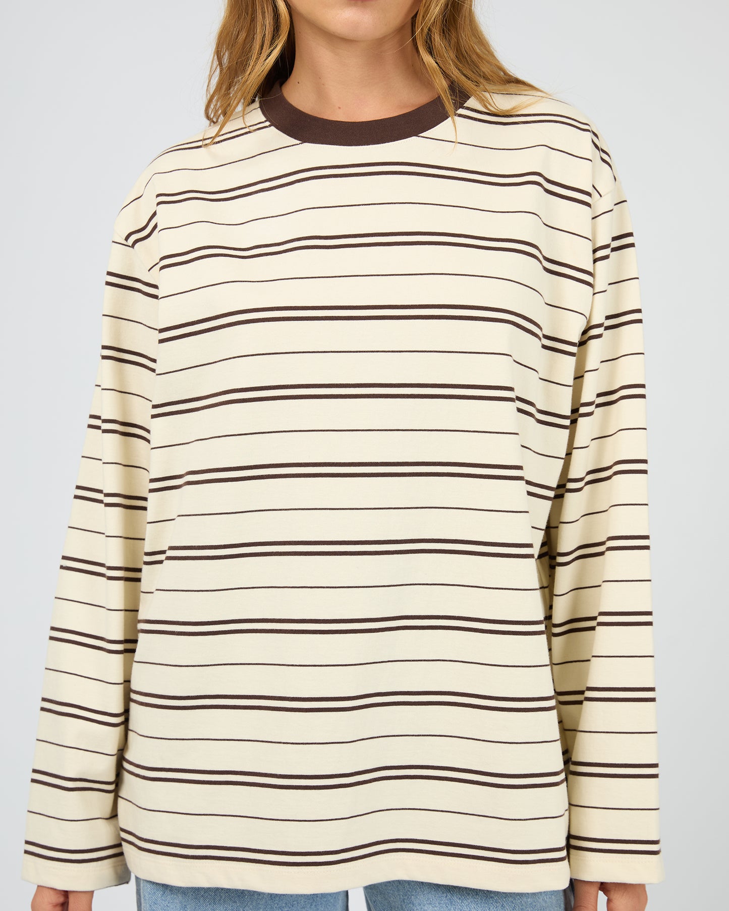 Person wearing a cream and brown striped long-sleeve shirt on a plain background. Stripe Long Sleeve Tee Chocolate - The Rose Edit