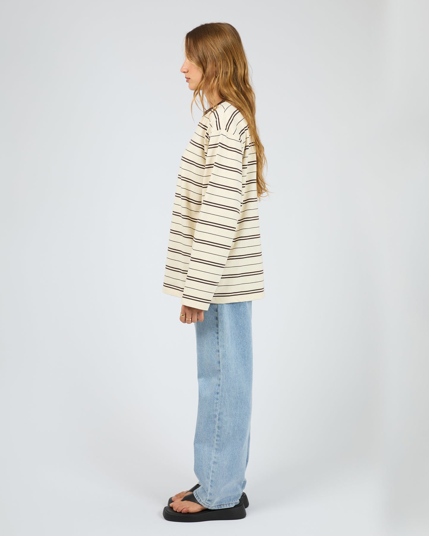 Person wearing a striped shirt and jeans on a white background. Stripe Long Sleeve Tee Chocolate - The Rose Edit